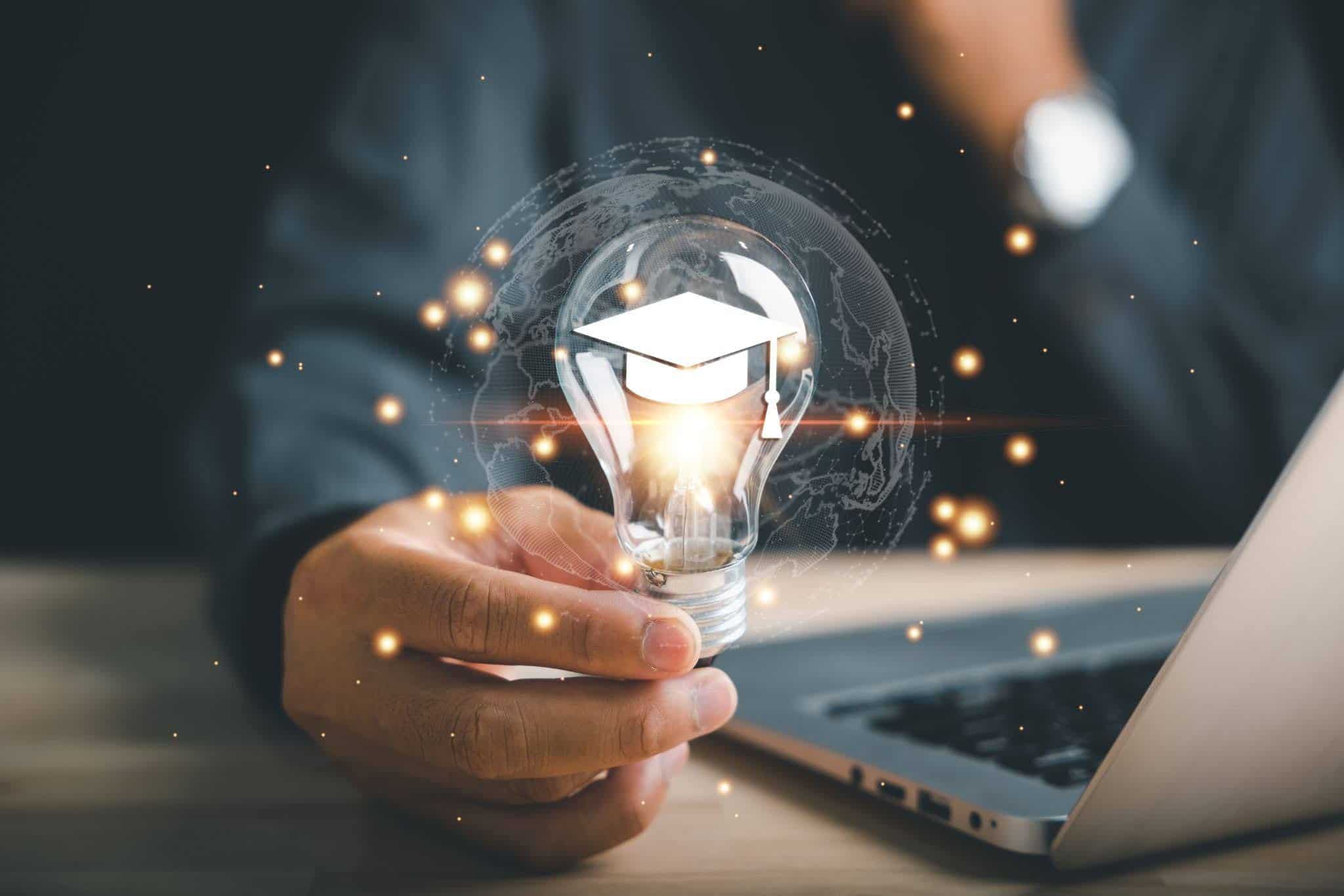 Hand holding a glowing lightbulb with a graduation cap, symbolising the path to higher education